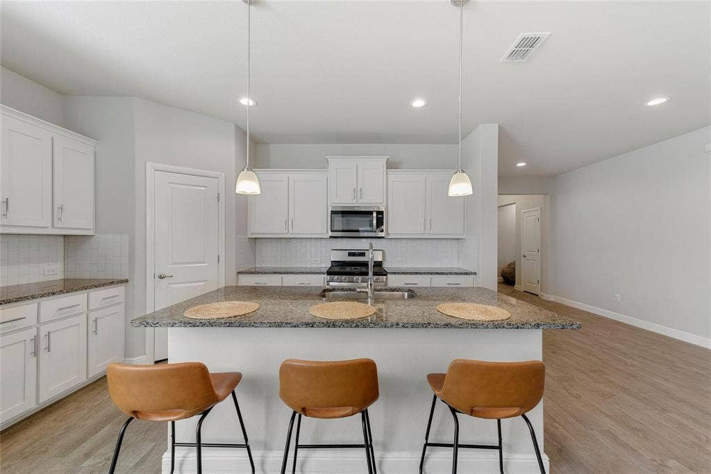 821 Shepperton Way, Fort Worth, TX 76247 Kitchen with hanging light fixtures, an island with sink, light wood-type flooring, and appliances with stainless steel finishes