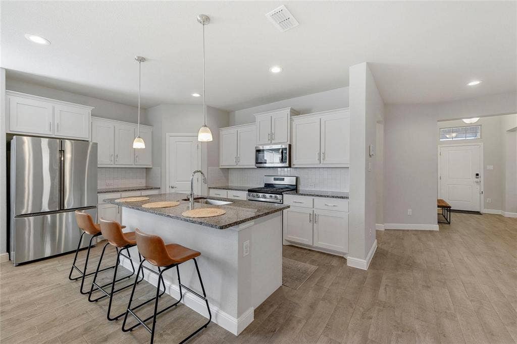 821 Shepperton Way, Fort Worth, TX 76247 Kitchen featuring light hardwood / wood-style floors, stainless steel appliances, sink, white cabinetry, and dark stone countertops