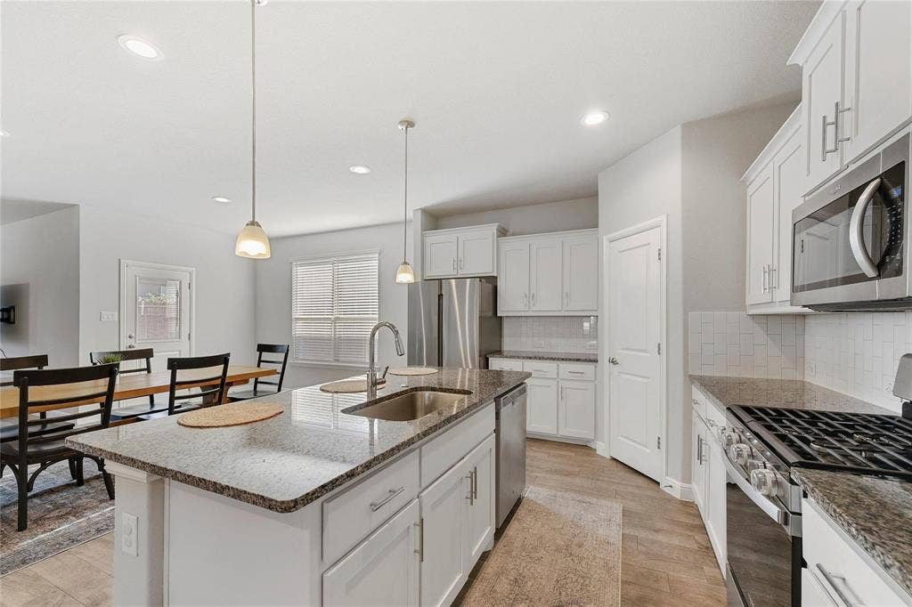 821 Shepperton Way, Fort Worth, TX 76247 Kitchen featuring stainless steel appliances, a center island with sink, sink, pendant lighting, and light hardwood / wood-style flooring