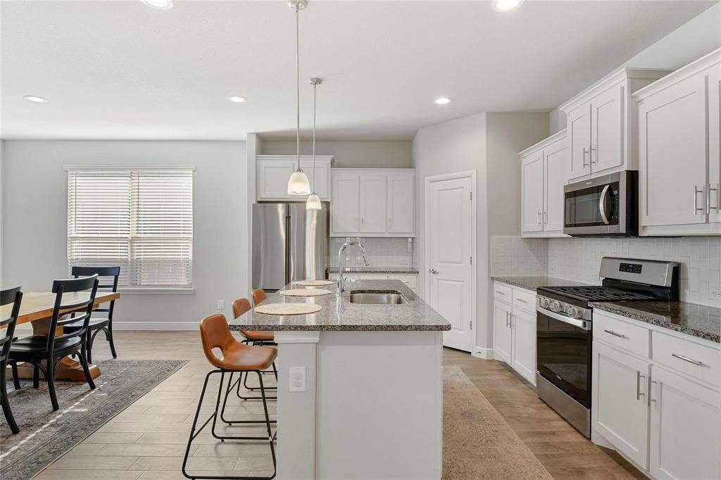 821 Shepperton Way, Fort Worth, TX 76247 Kitchen with a center island with sink, sink, appliances with stainless steel finishes, hanging light fixtures, and white cabinets