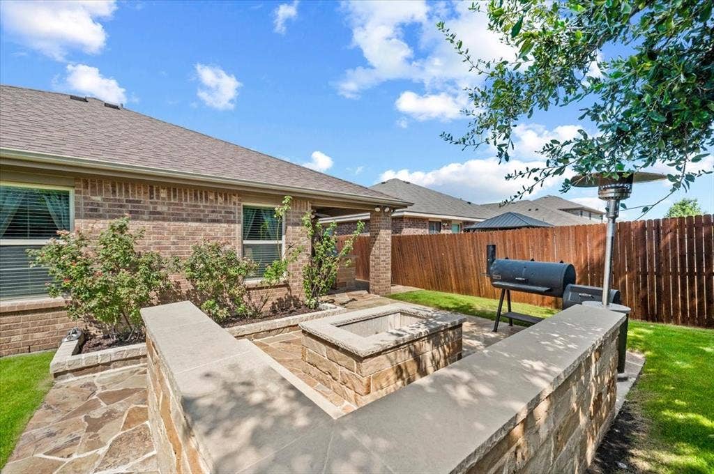 2225 Torch Lake Drive, Forney, TX 75126 Expansive backyard featuring a stone-clad fire pit, integrated stone seating, and a large grassy area