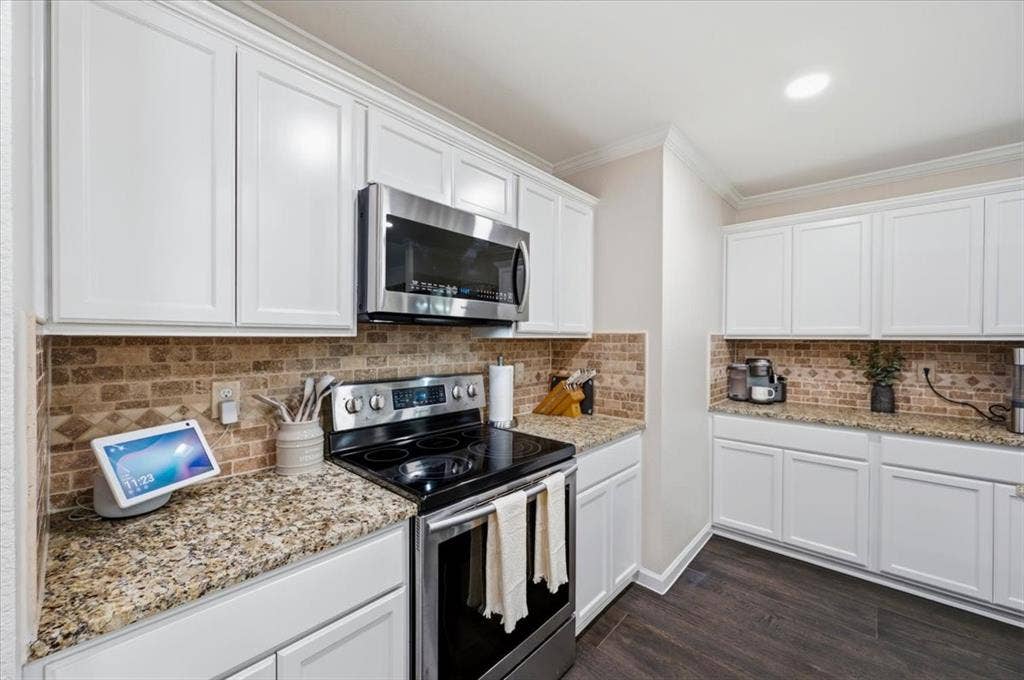 2225 Torch Lake Drive, Forney, TX 75126 Kitchen featuring white cabinetry, granite countertops, stainless steel appliances, brick-patterned backsplash, and wood-finish flooring