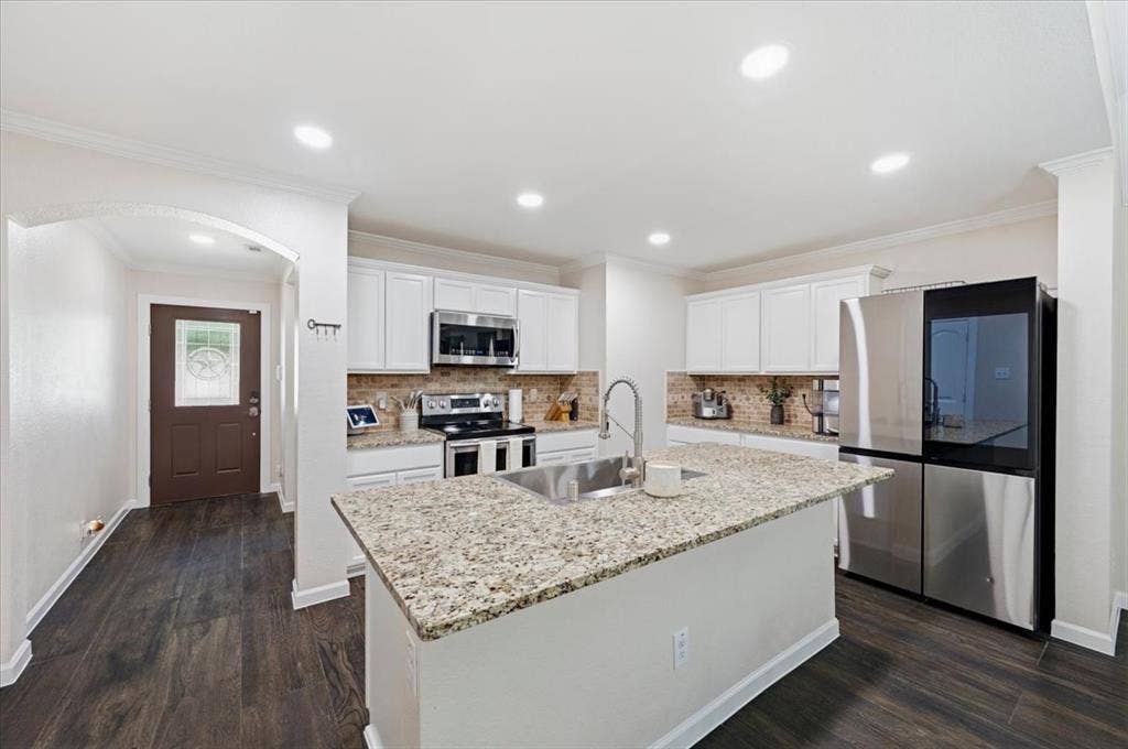 2225 Torch Lake Drive, Forney, TX 75126 Kitchen featuring an island with a stainless steel sink, granite countertops, white cabinetry, and stainless steel appliances