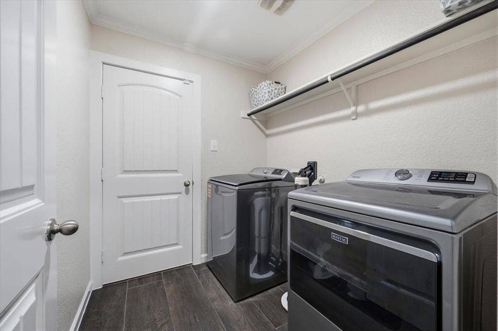 2225 Torch Lake Drive, Forney, TX 75126 Laundry area featuring dark wood-finish flooring, white walls, overhead shelving, and a white interior door with an arched panel design