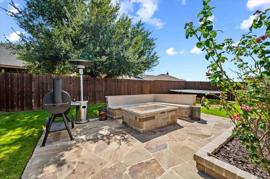 2225 Torch Lake Drive, Forney, TX 75126 Outdoor patio featuring flagstone paving, a built-in fire pit, and a built-in stone bench