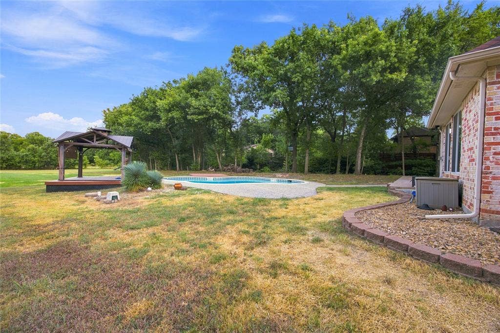 Backyard featuring an in-ground swimming pool, a wooden gazebo with a raised deck, and mature trees