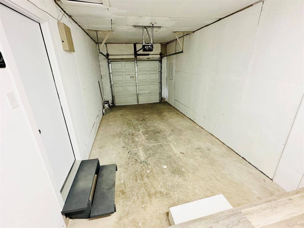 Garage space featuring a roll-up door, concrete flooring, and an interior access door