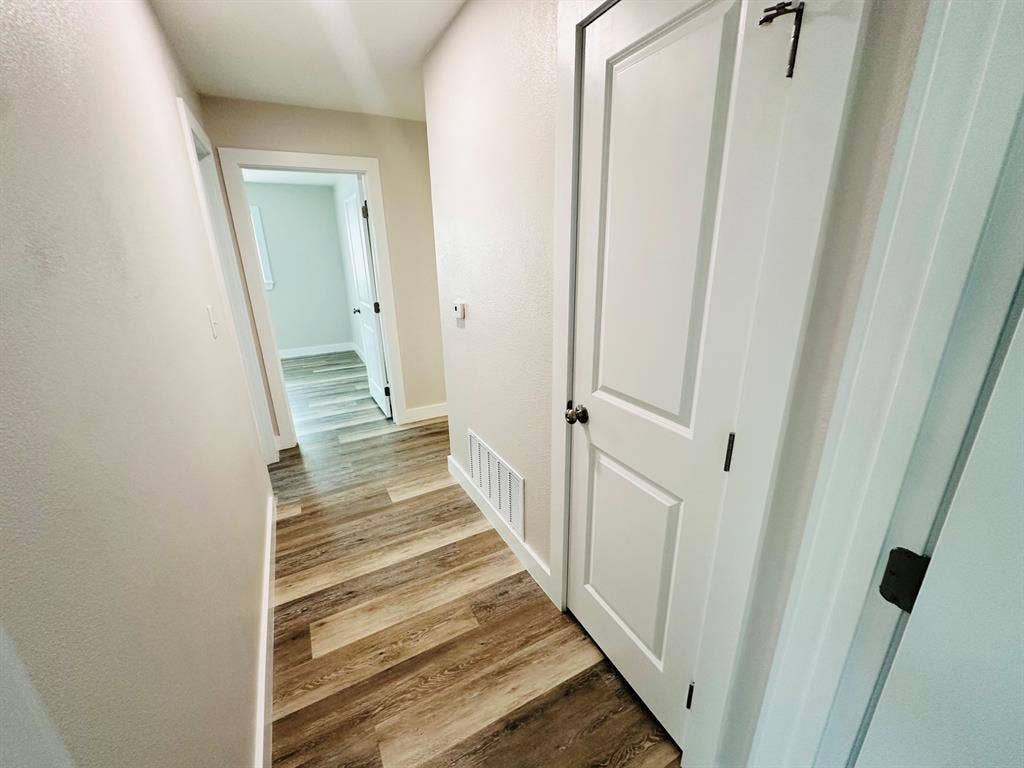 Wood-finish flooring throughout, white paneled doors, and light-toned walls