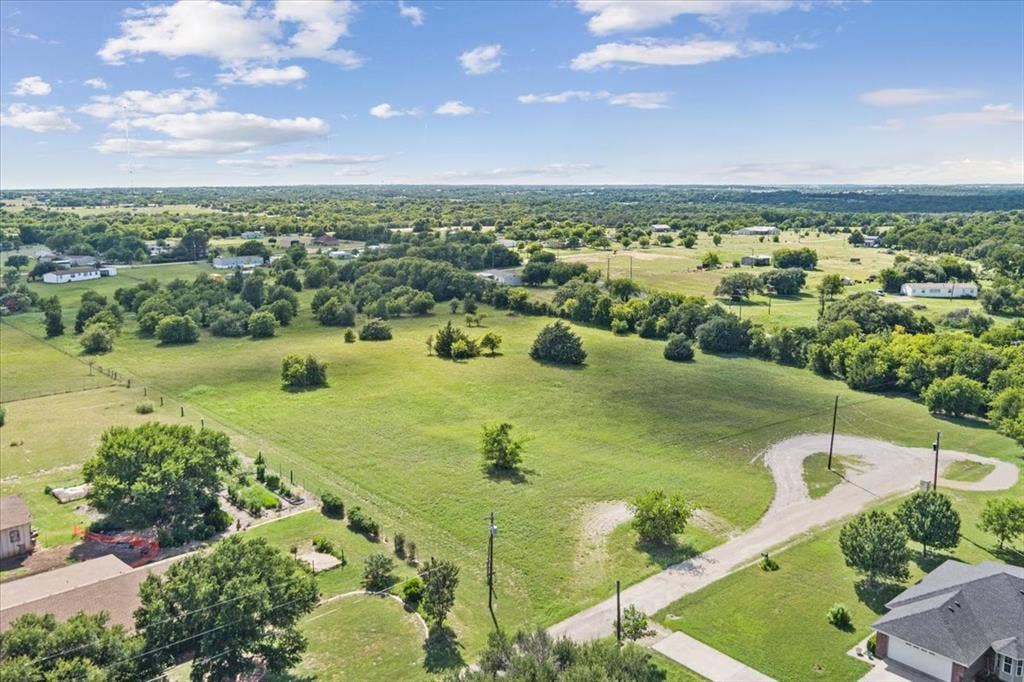 108 Brown Drive, Bruceville Eddy, TX 76524 Expansive green acreage with scattered mature trees and a gravel drive