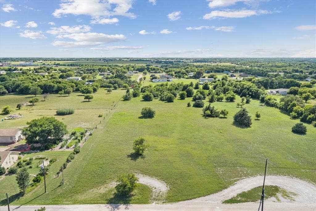 108 Brown Drive, Bruceville Eddy, TX 76524 Expansive green landscape with scattered trees, a partial garden area, and fencing