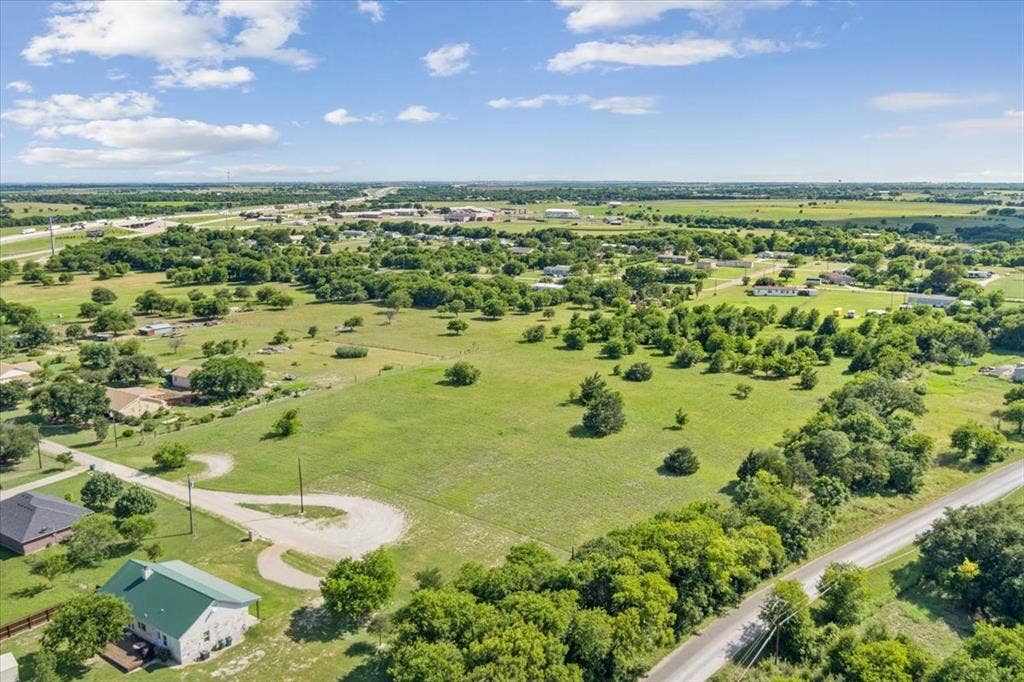 108 Brown Drive, Bruceville Eddy, TX 76524 Expansive parcel featuring a verdant landscape with scattered trees, bordered by a paved road