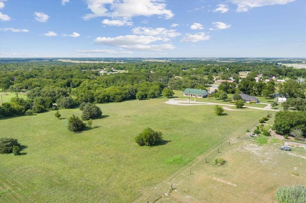 108 Brown Drive, Bruceville Eddy, TX 76524 Expansive green fields with scattered trees, a distant residential area, and a prominent building with a green roof