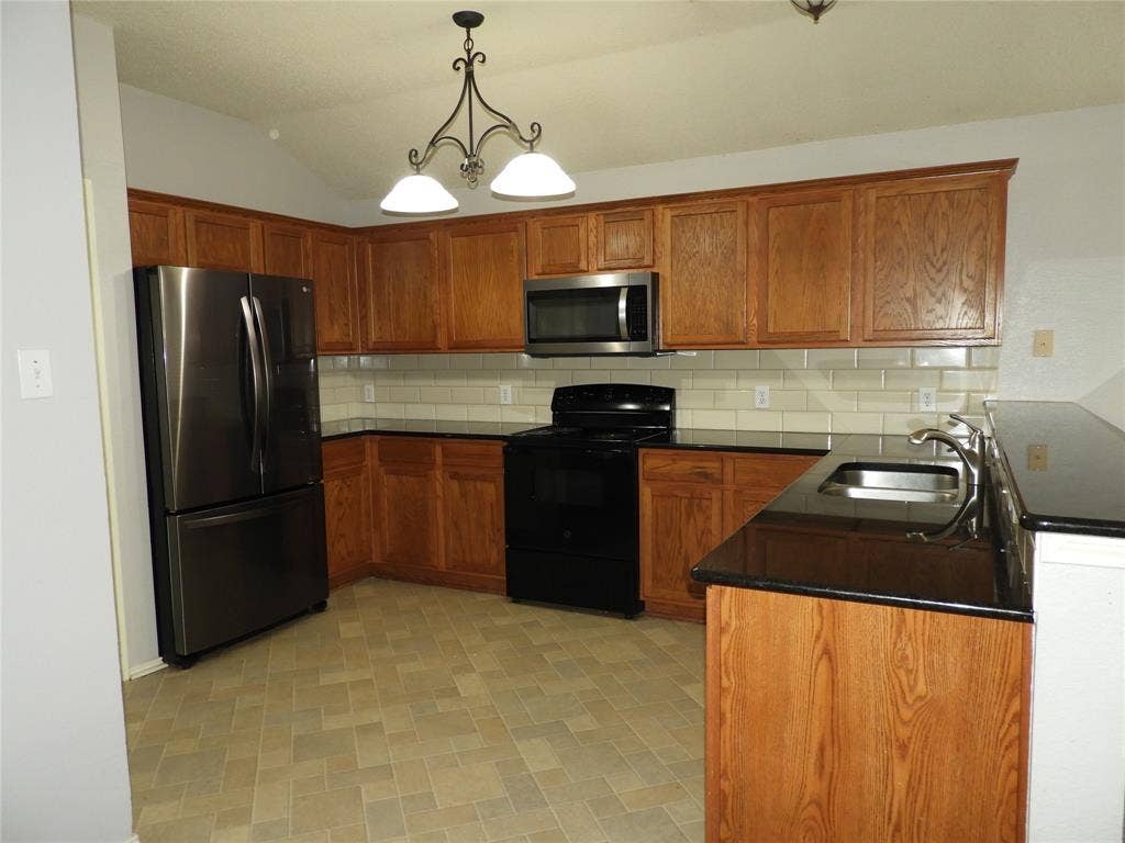 Kitchen featuring dark, granite countertops and black appliances.