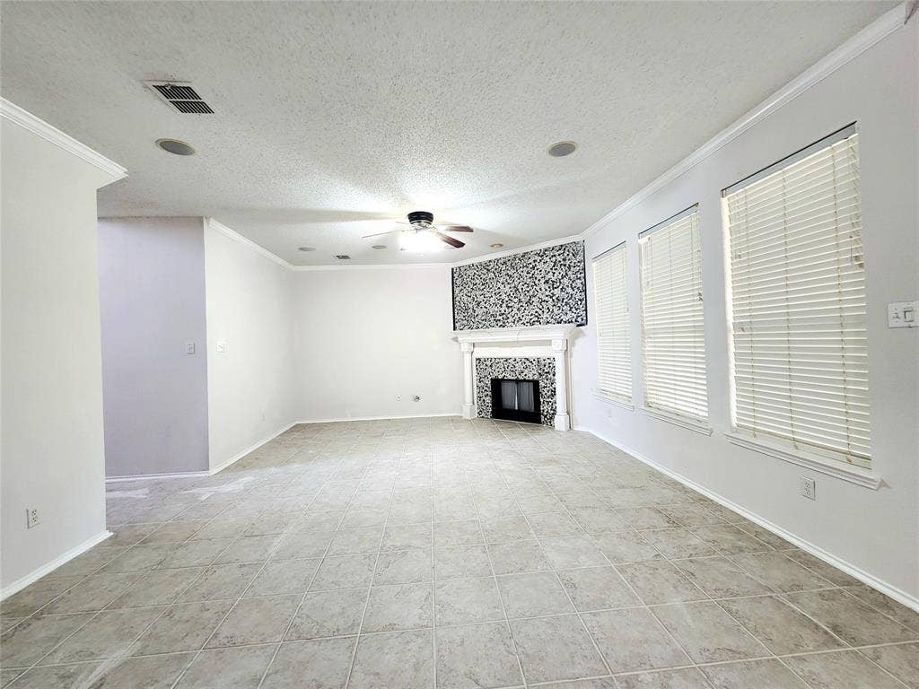 3625 Mason Drive, Plano, TX 75025 Tiled flooring, crown molding, built-in fireplace with decorative mantel, ceiling fan, and multiple windows with blinds