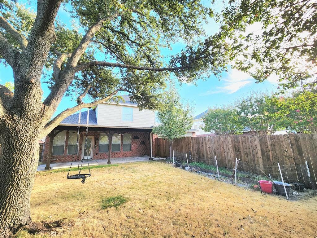 3625 Mason Drive, Plano, TX 75025 Expansive backyard featuring a mature tree, wood privacy fencing, and a covered patio with exposed beam supports