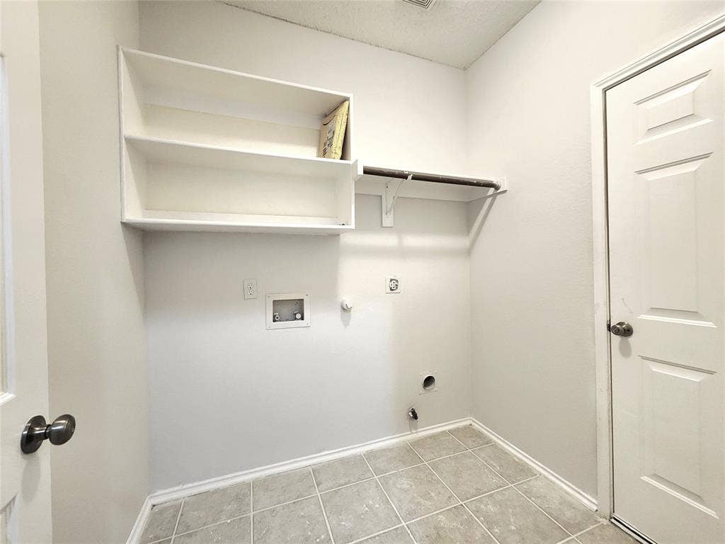 3625 Mason Drive, Plano, TX 75025 Laundry area featuring light-toned tile flooring, built-in shelving, and a wall-mounted hanging rod
