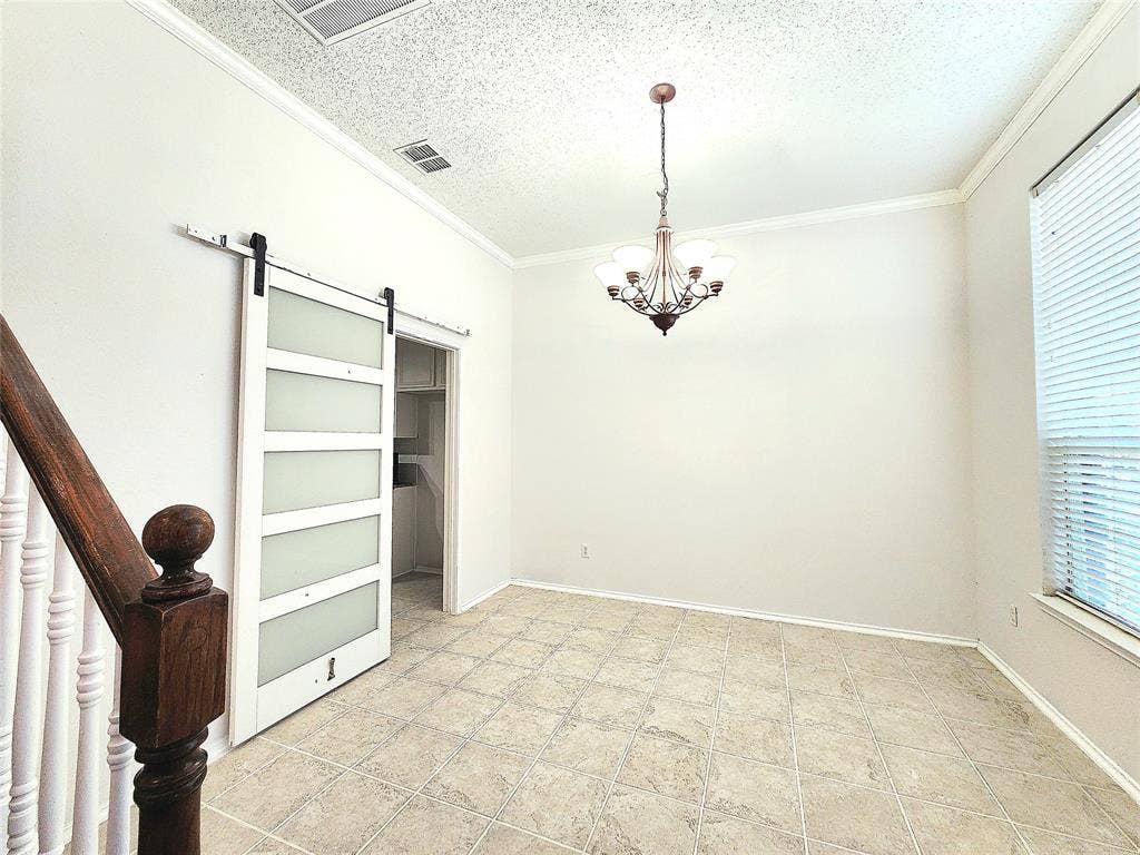 3625 Mason Drive, Plano, TX 75025 Decorative chandelier, crown molding, white barn door with frosted glass panels, wood staircase with white balusters, and square tile flooring