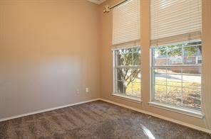 Unfurnished room featuring baseboards and dark carpet