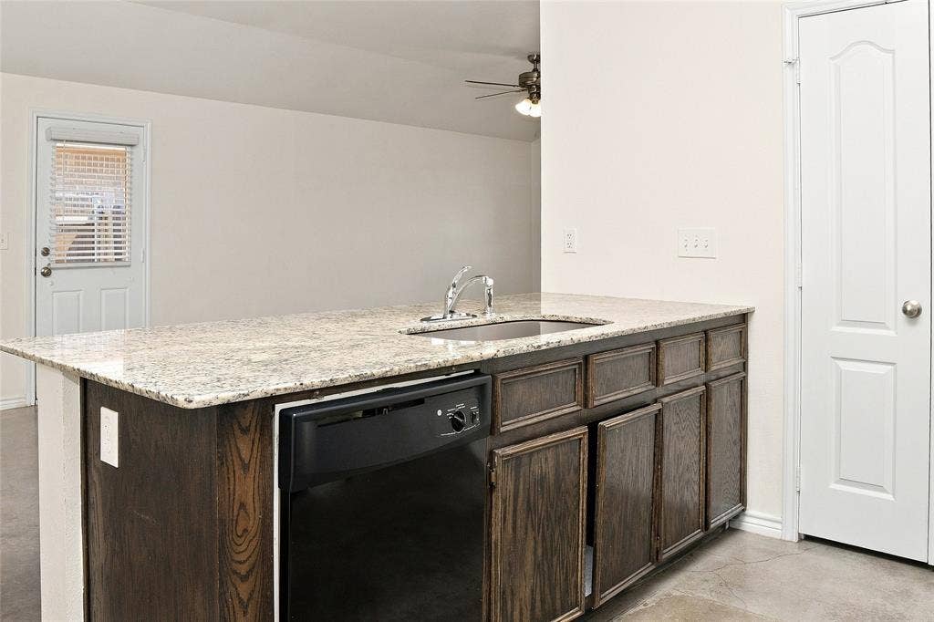 6015 Amelia Earhart Boulevard, #B, Killeen, TX 76543 Kitchen island featuring a stainless steel sink, a dishwasher, wood-finish cabinetry, and a light-toned countertop