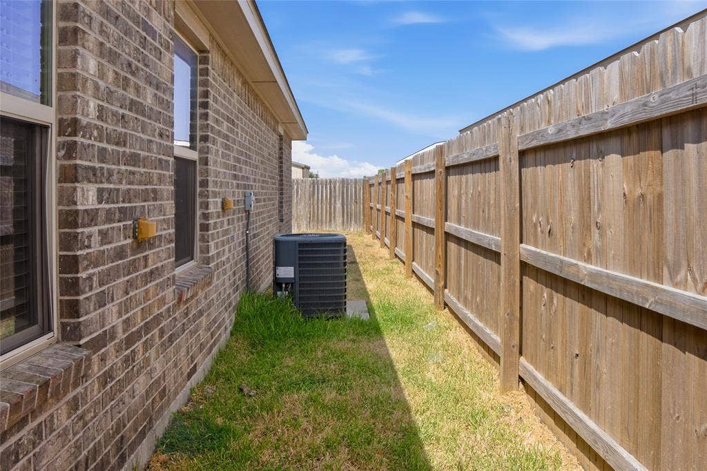 6015 Amelia Earhart Boulevard, #B, Killeen, TX 76543 Brick exterior with multiple windows, air conditioning unit, and wood privacy fencing