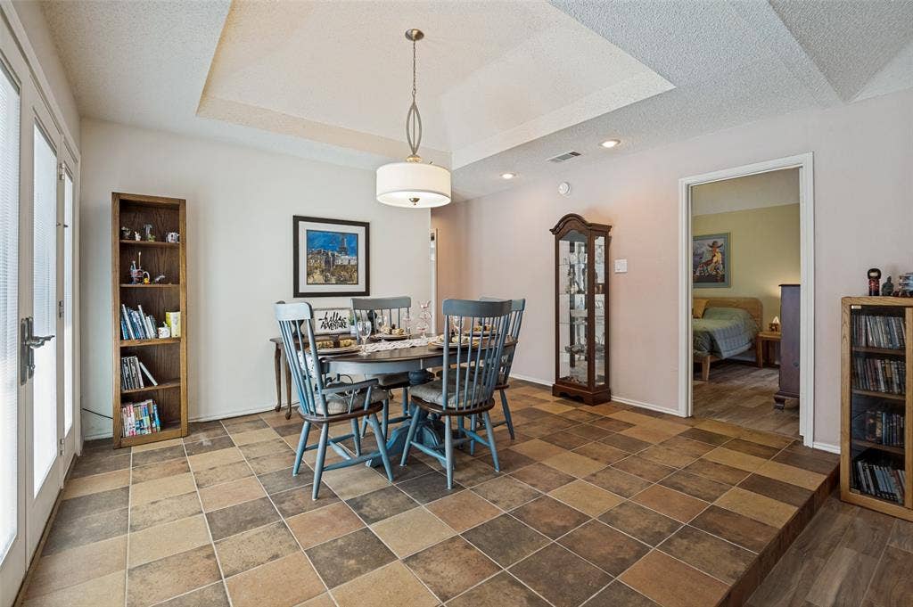 Dining area with multi-tone tile flooring, tray ceiling, recessed lighting, and a drum pendant light fixture