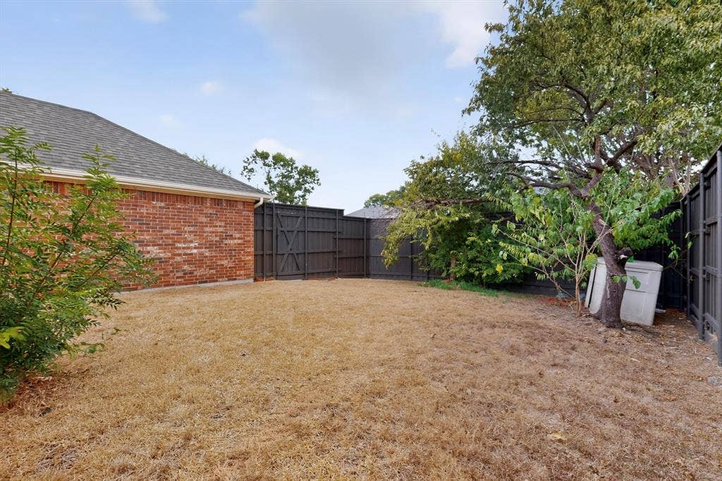 8108 Case Drive, Plano, TX 75025 Brick exterior featuring a shingled roof, dark-stained privacy fencing, and mature trees