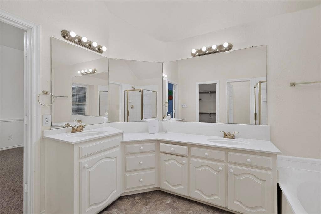 8108 Case Drive, Plano, TX 75025 White cabinetry with integrated sinks, expansive wall-mounted mirrors, and an adjacent built-in soaking tub