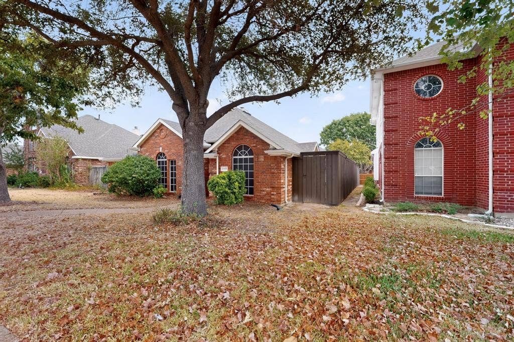 8108 Case Drive, Plano, TX 75025 Brick exterior featuring arched windows, mature landscaping, and a side yard with privacy fencing