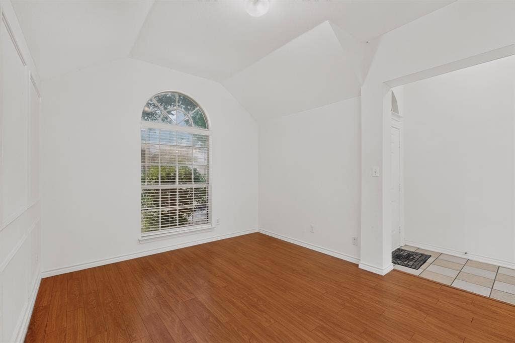 8108 Case Drive, Plano, TX 75025 Vaulted ceiling, arched window with blinds, wood-finish flooring, white paneled wall, tiled entry