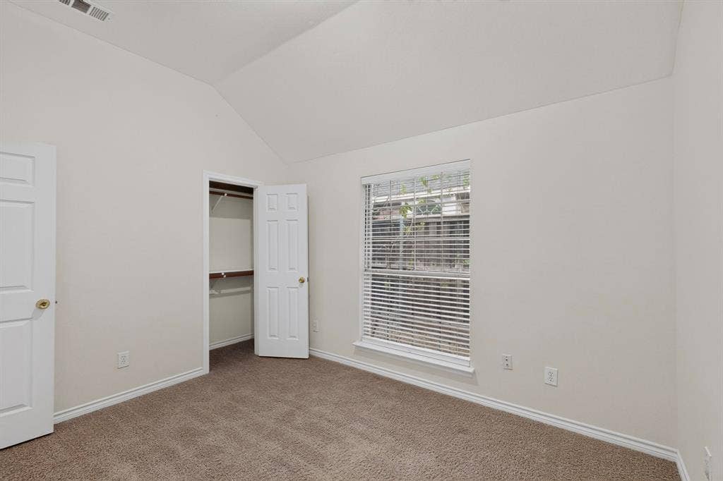 8108 Case Drive, Plano, TX 75025 Vaulted ceiling, neutral wall paint, carpet flooring, a window with blinds, and built-in closet shelving