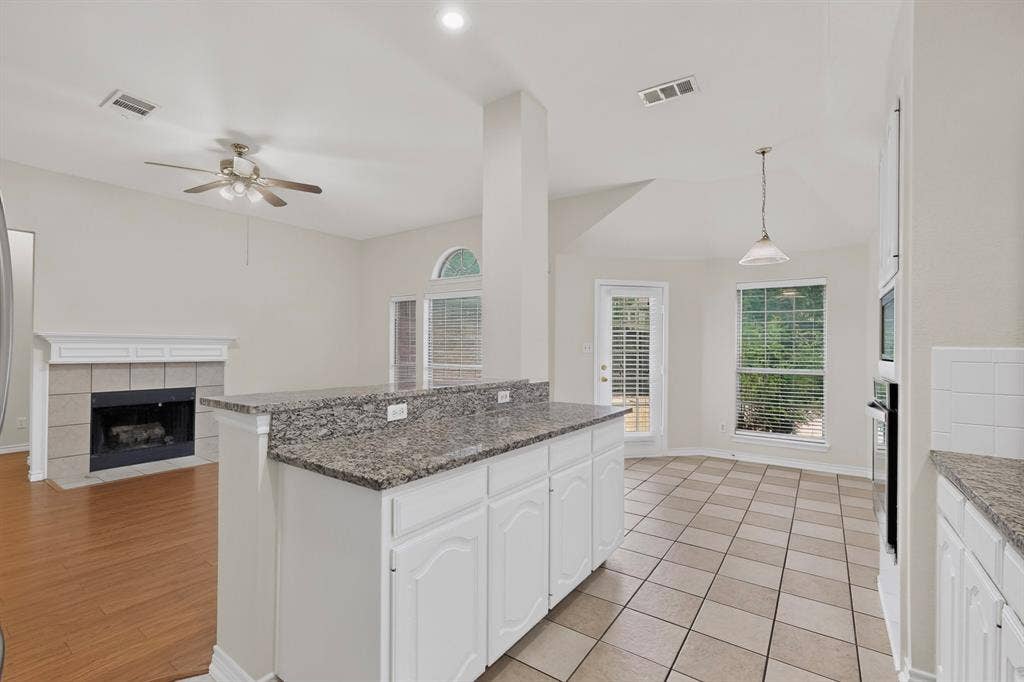 8108 Case Drive, Plano, TX 75025 Kitchen island featuring a granite countertop and white cabinetry