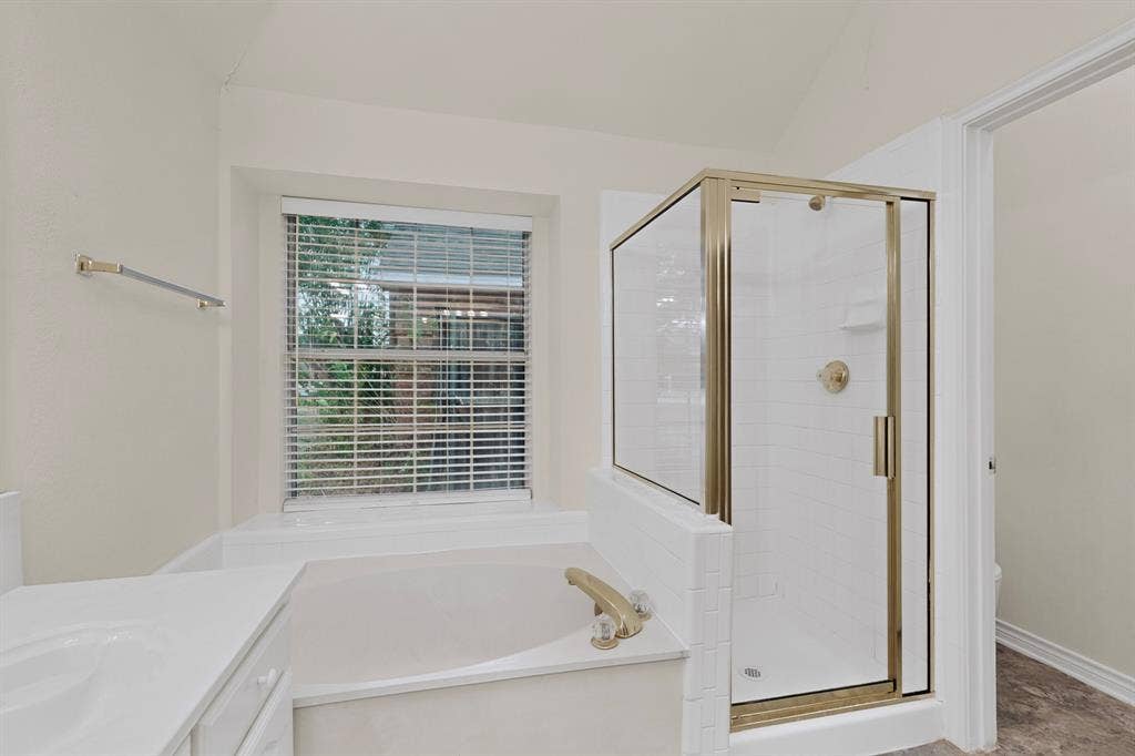 8108 Case Drive, Plano, TX 75025 Built-in soaking tub with gold-tone fixtures, separate shower with glass enclosure, white tile surround, and a vanity with an integrated sink
