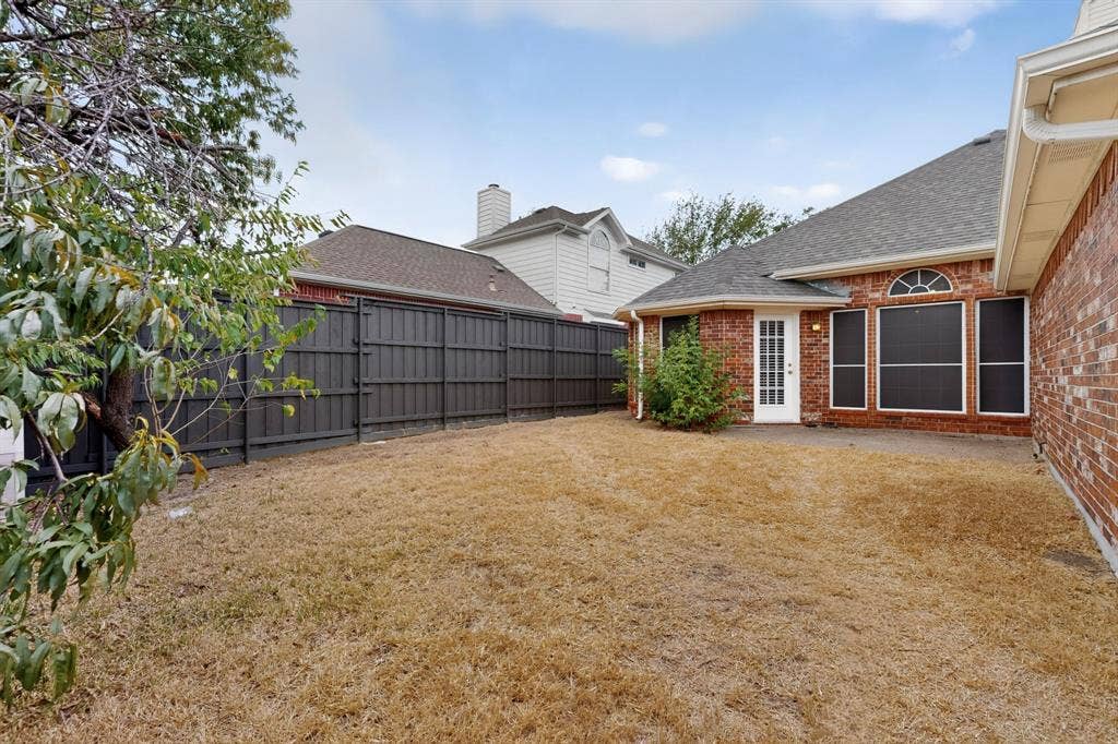 8108 Case Drive, Plano, TX 75025 Private backyard featuring a dark wood fence and a brick exterior with a white door
