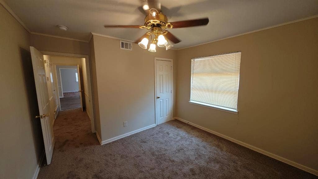 Carpeted room featuring a ceiling fan with light fixture, window with blinds, and white paneled doors