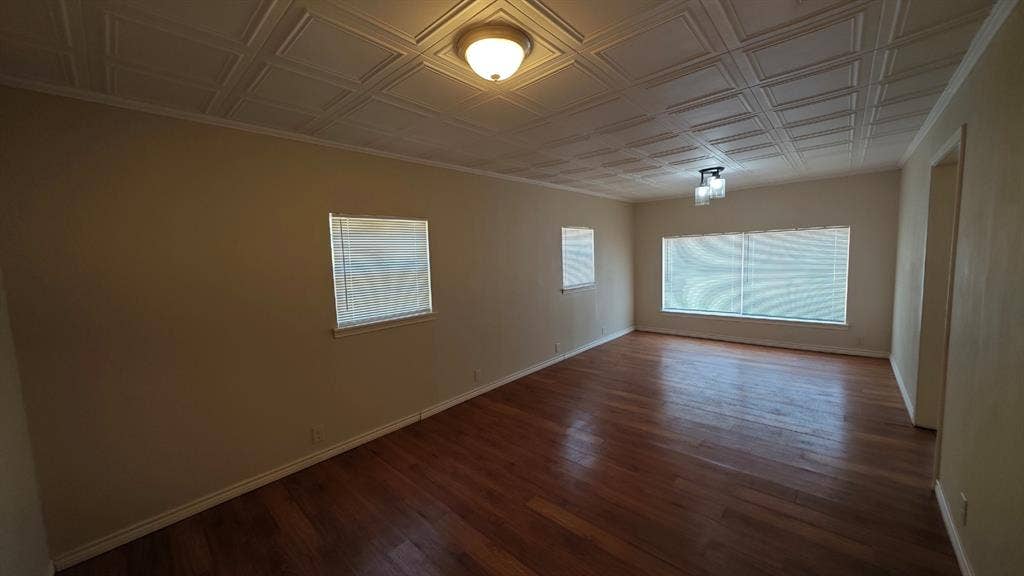 Hardwood flooring, textured ceiling with decorative panels, multiple windows with blinds, and flush-mount lighting fixtures