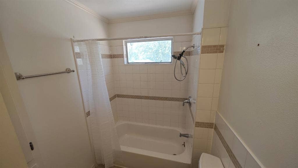 Tub and shower combination with tiled surround, decorative accent tile, and a window