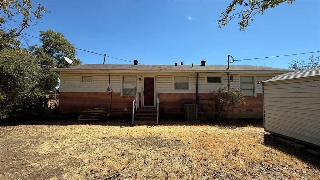Rear exterior with light-colored siding and a brick-finish lower section