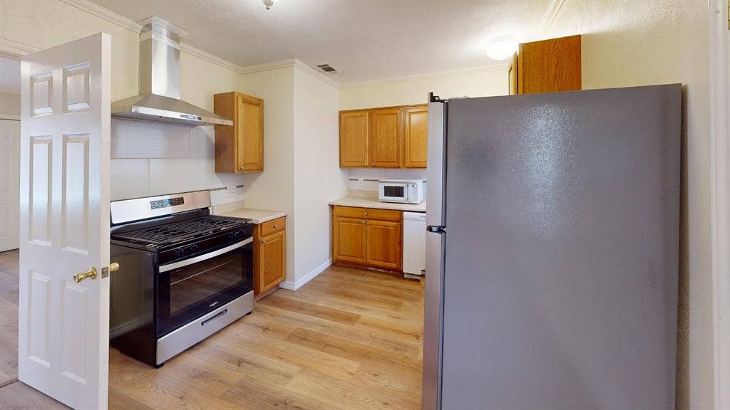 Kitchen featuring wood-finish flooring, recessed lighting, wood cabinetry, stainless steel range with hood, and white countertops