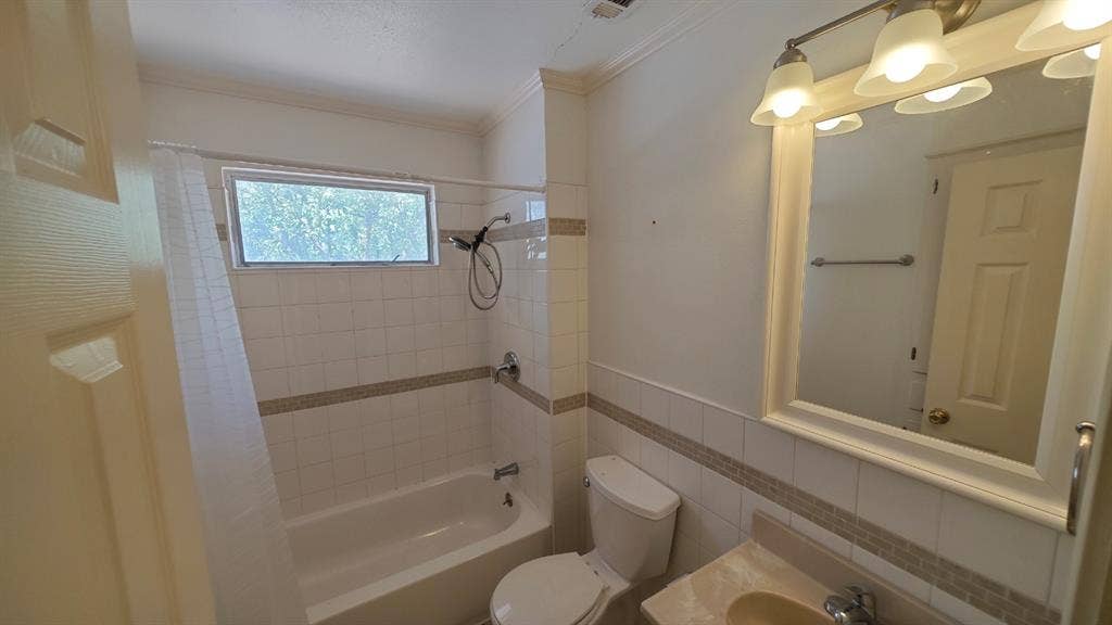 Bathroom featuring a tiled shower-tub combination with a window, a single vanity with a mounted mirror, and a three-light fixture