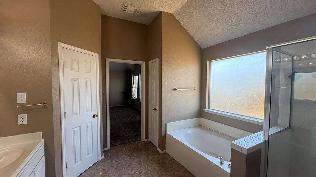 1433 Winterwood Drive, Allen, TX 75002 Vaulted ceiling, built-in bathtub, glass-enclosed shower, frosted window, and dual vanity countertop