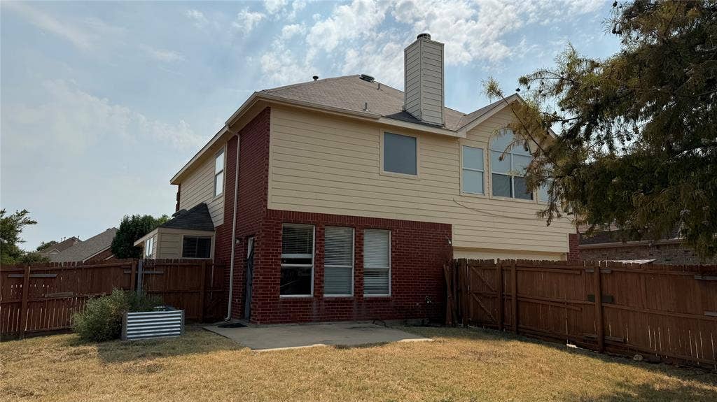 1433 Winterwood Drive, Allen, TX 75002 Two-story exterior with brick and siding facade, private wood fencing, ground-level patio, and chimney feature