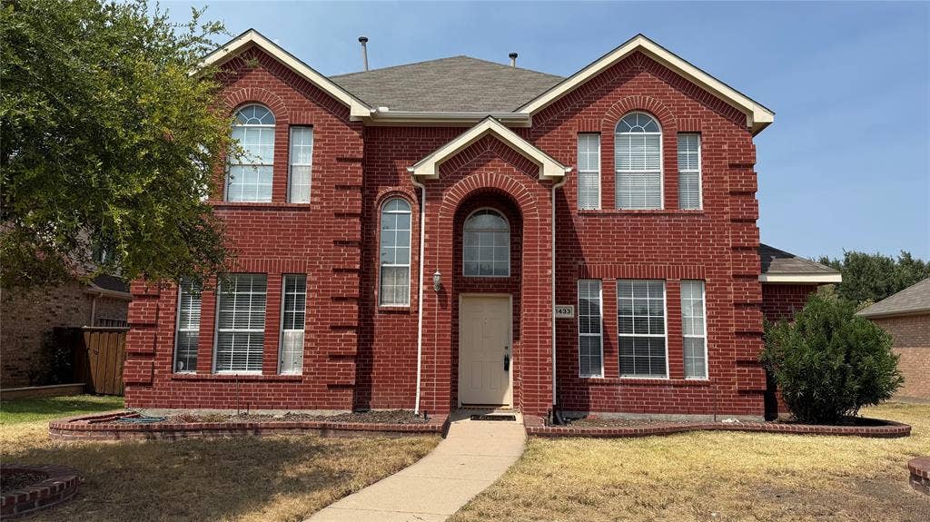 1433 Winterwood Drive, Allen, TX 75002 Red brick facade with arched windows, prominent entry archway, and a concrete pathway