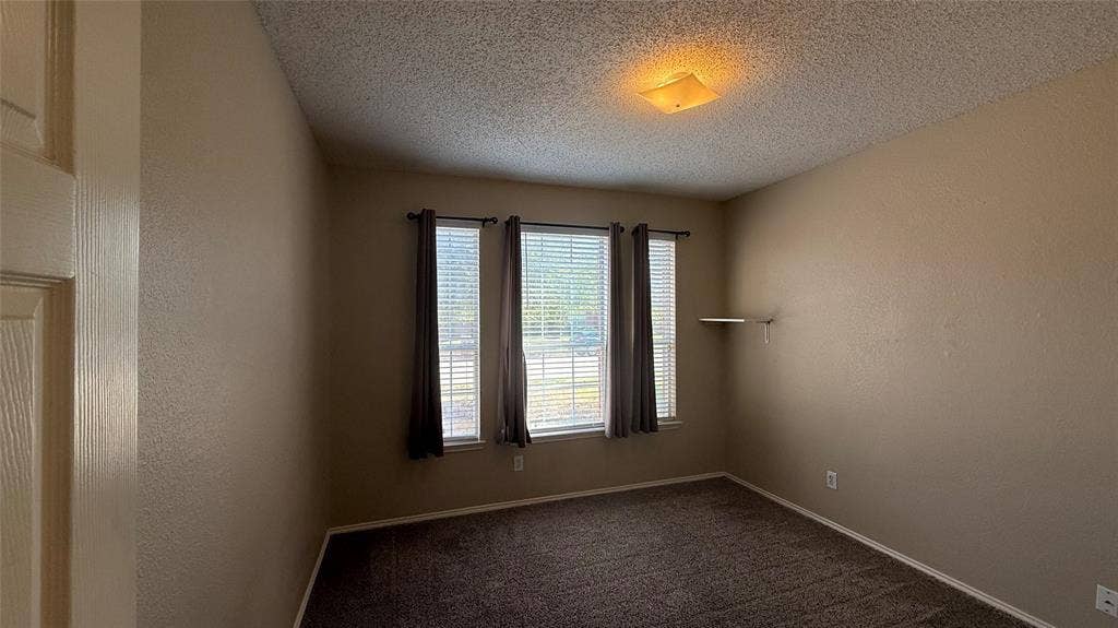 1433 Winterwood Drive, Allen, TX 75002 Room featuring neutral wall tones, textured ceiling, and dark carpet
