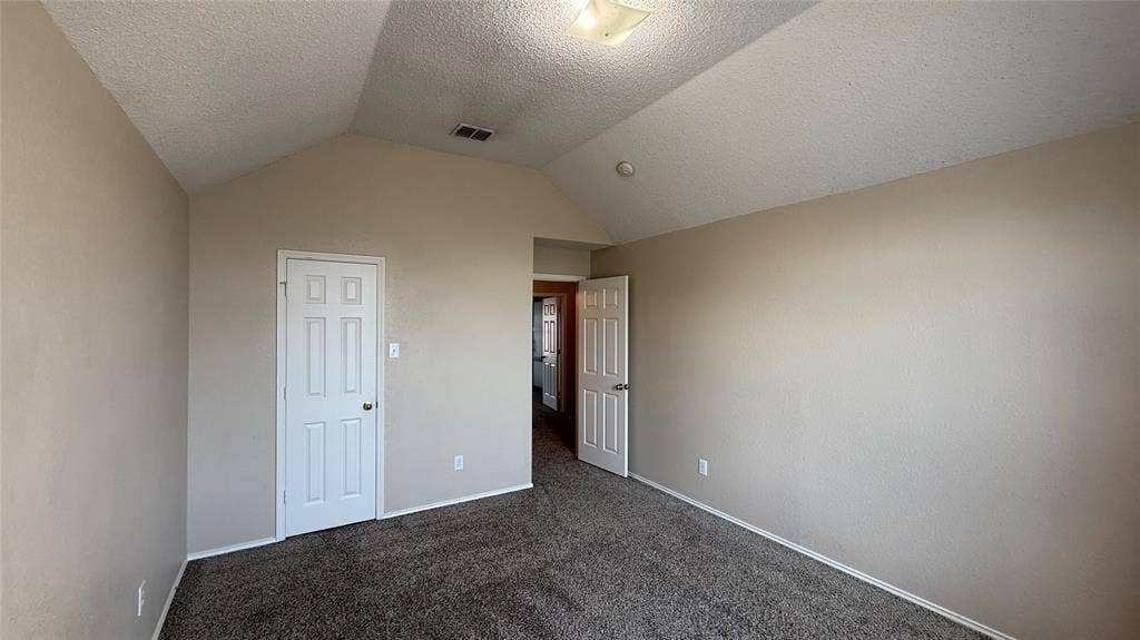 1433 Winterwood Drive, Allen, TX 75002 Vaulted ceiling, neutral tone walls, dark carpet flooring, white paneled doors, and a flush mount ceiling light fixture