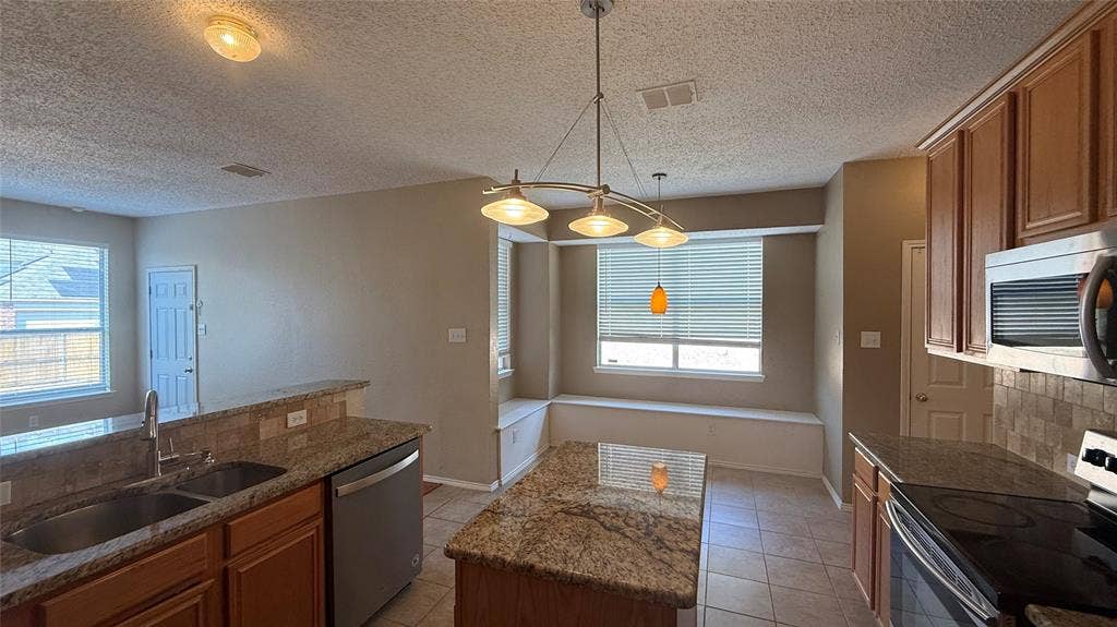 1433 Winterwood Drive, Allen, TX 75002 Kitchen featuring a double basin sink, stainless steel dishwasher, built-in microwave, and a breakfast bar with granite countertops
