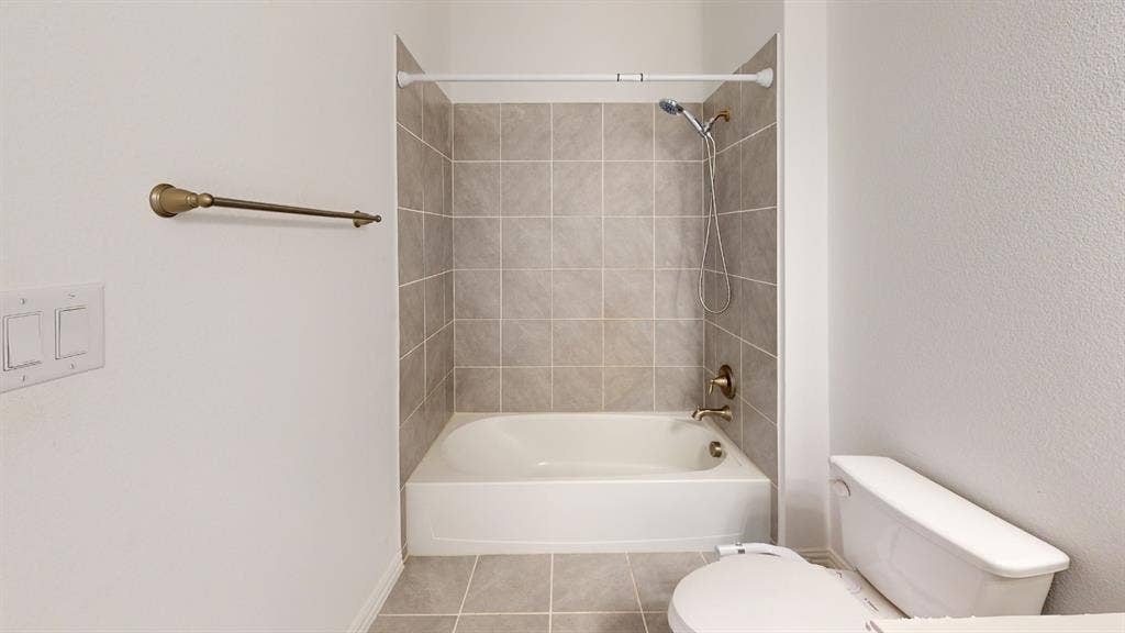 3285 Dover Drive, McKinney, TX 75069 Bathtub with a tiled surround, overhead shower, and adjacent commode