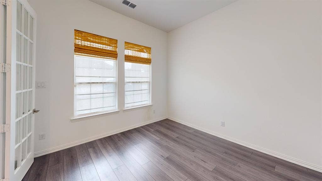 3285 Dover Drive, McKinney, TX 75069 Wood-finish flooring, white walls, and two large windows with horizontal blinds