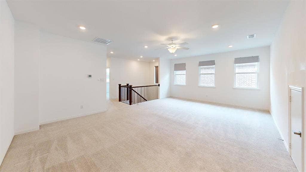 3285 Dover Drive, McKinney, TX 75069 Expansive carpeted area featuring recessed lighting, a ceiling fan, a dark wood and wrought iron staircase railing, and three windows with shades