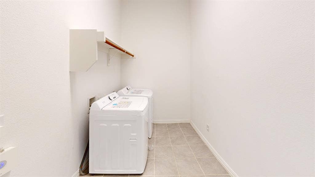 3285 Dover Drive, McKinney, TX 75069 Dedicated laundry area featuring a wall-mounted cabinet, wooden hanging rod, and tiled flooring