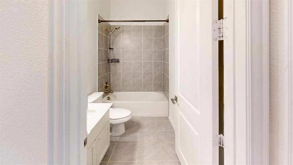3285 Dover Drive, McKinney, TX 75069 Bathroom featuring a white vanity with an integrated sink, ceramic floor tiling, and a tub with tiled surround